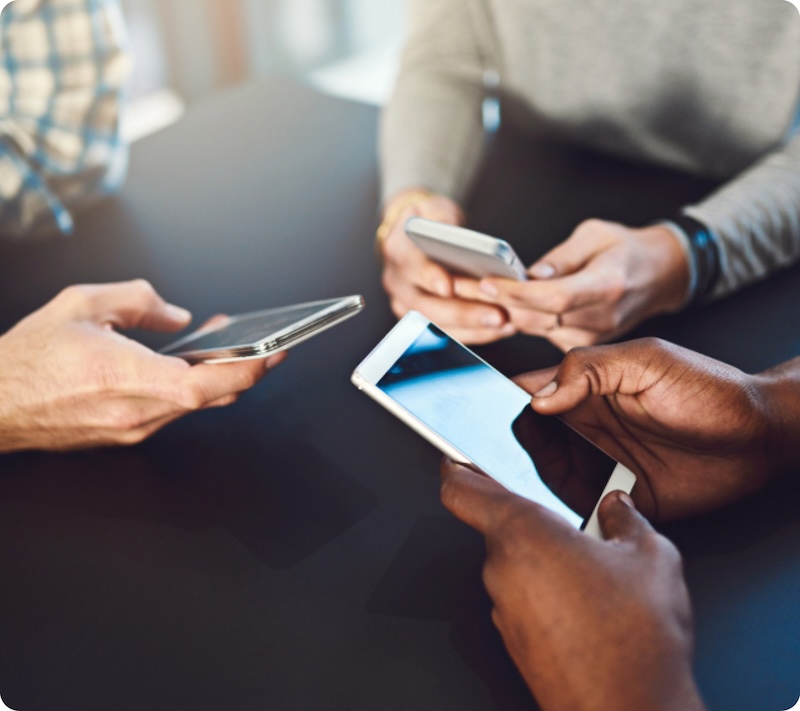 Drei Menschen halten ihre Smartphones zusammen.